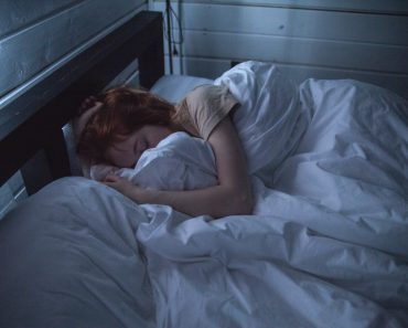 Kvinde sover i seng om natten med blå lys