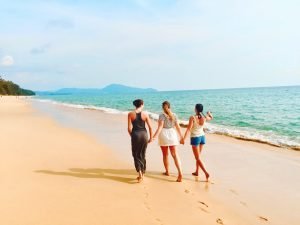 Tre kvinder går på strand og taler